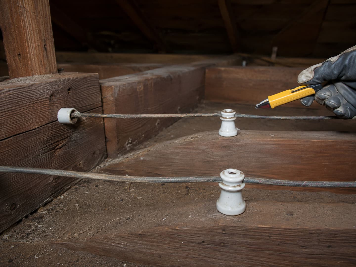 Electrician tracing active knob-and-tube circuits from an accessible attic area