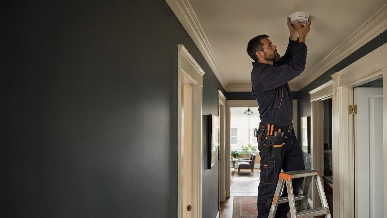 Electrician installing a smoke and carbon monoxide alarm in a San Francisco home